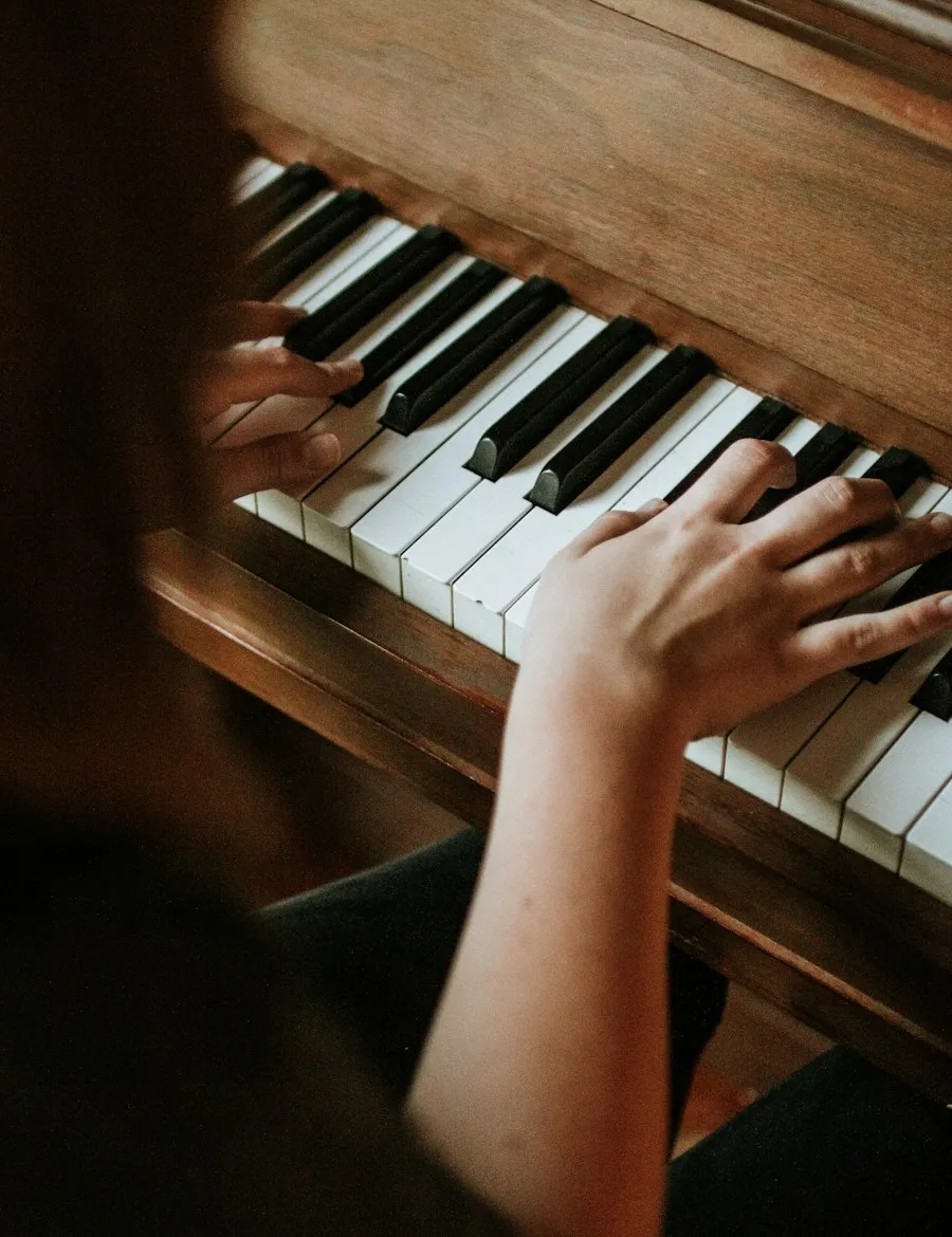 Pianist's hands playing an upright piano